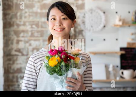 Femme de shopping souriante tenant un bouquet de fleurs Banque D'Images