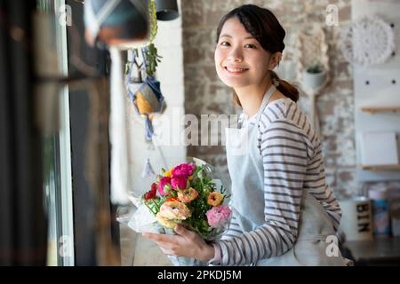 Femme souriante de magasin tenant un bouquet de fleurs Banque D'Images