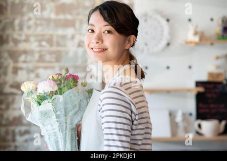 Femme souriante de magasin tenant un bouquet de fleurs Banque D'Images