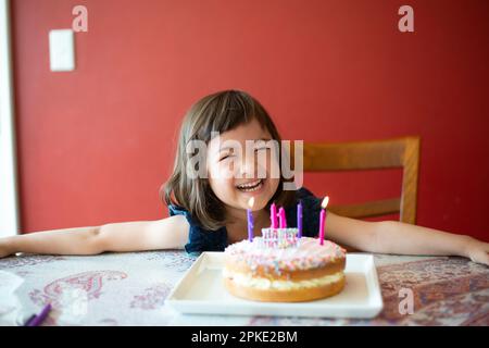 Fille riant devant le gâteau d'anniversaire Banque D'Images