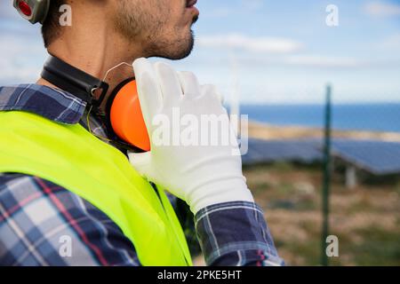 Gros plan d'un ingénieur portant des cache-oreilles pour protéger son audition dans une usine. Banque D'Images