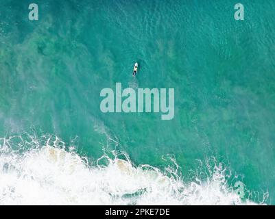 Vue d'en haut, vue aérienne stupéfiante d'une personne surfant sur un océan turquoise. Fuerteventura, Îles Canaries, Espagne. Banque D'Images