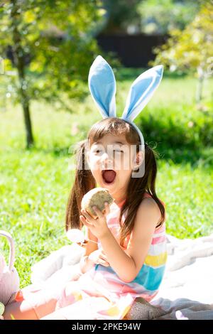 Fille essayant de manger un petit pain chaud de Pâques Banque D'Images