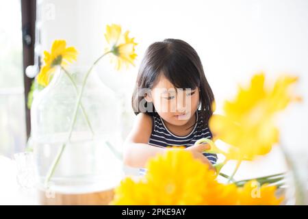 Fille avec fleurs jaunes dans un vase Banque D'Images