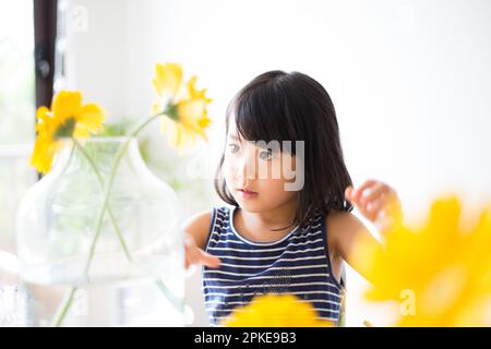 Fille avec fleurs jaunes dans un vase Banque D'Images