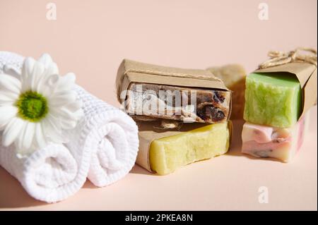 Encore plus de vie avec spa set: Serviettes blanches roulées et des barres de savon maison bio pressés à froid, isolé sur fond rose Banque D'Images