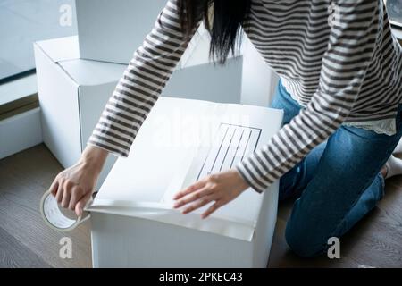 Femme mettant le ruban adhésif sur le carton Banque D'Images