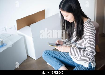 Femme touchant son téléphone entouré de carton mobile Banque D'Images