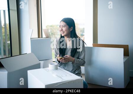 Femme touchant son smartphone entouré de carton mobile Banque D'Images