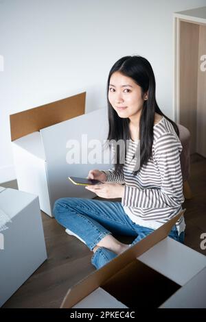 Femme touchant son téléphone entouré de carton mobile Banque D'Images