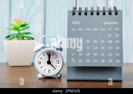 Décembre 2023 Calendrier mensuel de bureau pour 2023 ans avec réveil sur fond bleu en bois. Banque D'Images