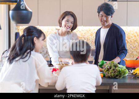 Un couple debout dans la cuisine et un frère et une sœur qui parlent Banque D'Images