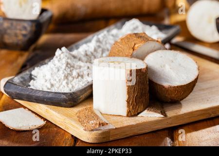 Pile de manioc, de manioc et de farine de manioc sur fond de bois rustique (Manihot esculenta) Banque D'Images