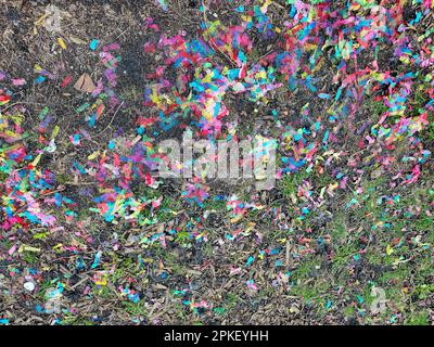 Le papier coloré confetti dans la saleté et l'herbe sur le sol Banque D'Images