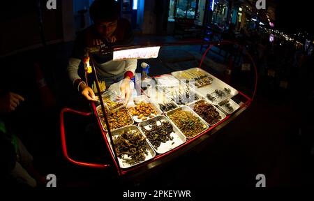 24 février 2023-Bangkok Thaïlande-araignées, scorpions, cafards, criquets frits dans des poêles à frire et exposés pour la vente dans une rue bondée dans le centre Banque D'Images