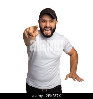 Portrait d'un homme barbu péévreux avec chapeau noir, hurle avec colère à quelqu'un, pointe avec l'index directement à l'appareil photo, habillé en t-shirt blanc, blam Banque D'Images