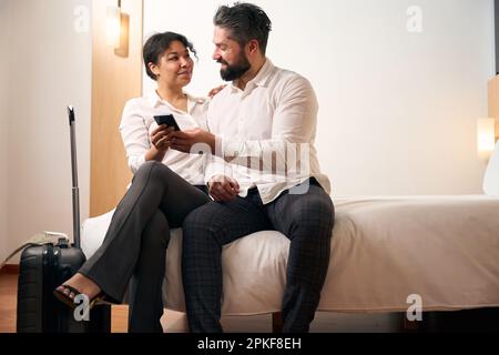 Femme élégante et son compagnon assis dans la chambre d'hôtel Banque D'Images