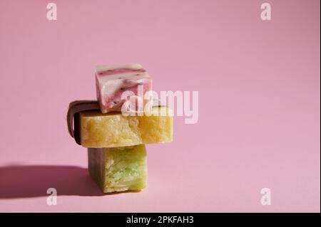 Pile de savon écologique naturel fait maison avec des ingrédients à base de plantes biologiques pour la santé et le spa, isolé sur fond rose Banque D'Images