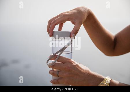 Gros plan des mains d'une femme ouvrant une bouteille d'eau. Banque D'Images