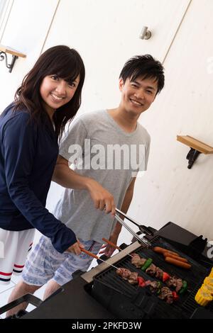 Un jeune couple fait griller de la viande sur le gril Banque D'Images