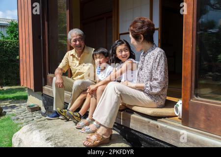 Un couple âgé et leurs petits-enfants assis sur le porche Banque D'Images