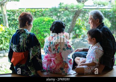 Grands-parents et petits-enfants assis sur le porche Banque D'Images