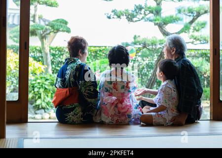 Grands-parents et petits-enfants assis sur le porche Banque D'Images