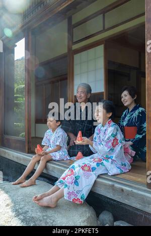 Grands-parents et petits-enfants assis sur le porche Banque D'Images