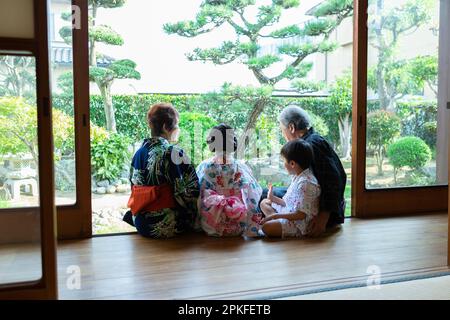 Grands-parents et petits-enfants assis sur le porche Banque D'Images