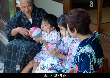 Frères et sœurs et grands-parents jouant avec des ballons en papier Banque D'Images