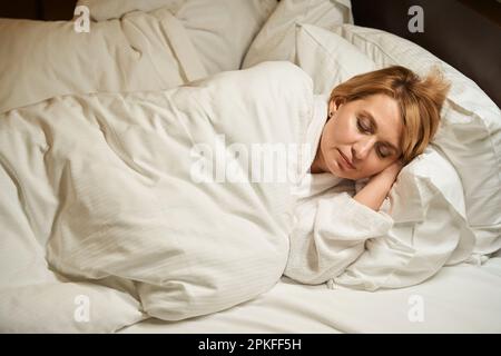 Belle femme d'âge moyen prend une petite sieste sur un oreiller doux Banque D'Images