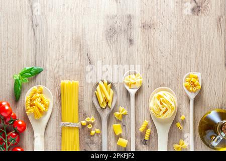 Diverses pâtes en cuillères, tomates, basilic et huile d'olive. Plan d'agencement avec vue de dessus Banque D'Images