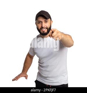 Portrait d'un homme barbu péévreux avec chapeau noir, hurle avec colère à quelqu'un, pointe avec l'index directement à l'appareil photo, habillé en t-shirt blanc, blam Banque D'Images