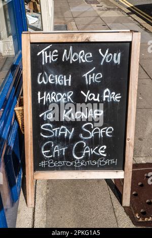 Panneau publicitaire drôle devant un café et un bakeshop. Restez en sécurité, mangez du gâteau, du Blackboard, de l'humour. Humour. Panneau de tableau noir. Angleterre. Concept, Résumé. Banque D'Images