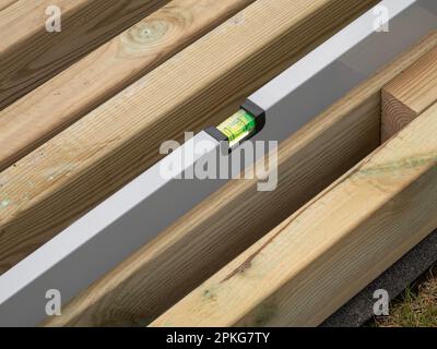 Niveau à bulle vérifiant le niveau d'une planche de bois. Gros plan. Banque D'Images