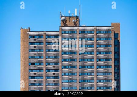 Plan horizontal d'une tour d'appartements avec équipement de communication sur le toit sous un ciel bleu clair. Banque D'Images