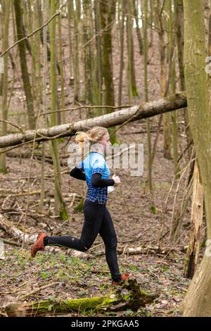 Grodno, Bélarus - 26 mars 2023 : une jeune fille adorable portant des vêtements de sport traversant une forêt pendant un exercice dans la forêt de Grodno Banque D'Images