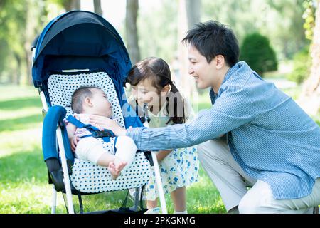 Parents et enfants regardant bébé dans la poussette Banque D'Images