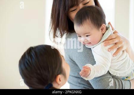 Les sœurs se regardant les unes les autres et souriantes, la mère regardant Banque D'Images