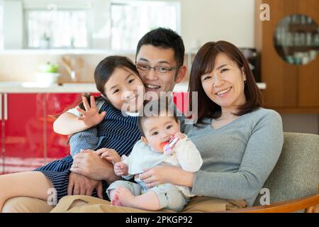 Family sitting on couch and smiling Stock Photo