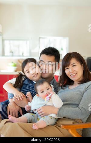 Family sitting on couch and smiling Stock Photo