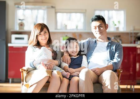 Famille assise sur le canapé et souriante Banque D'Images