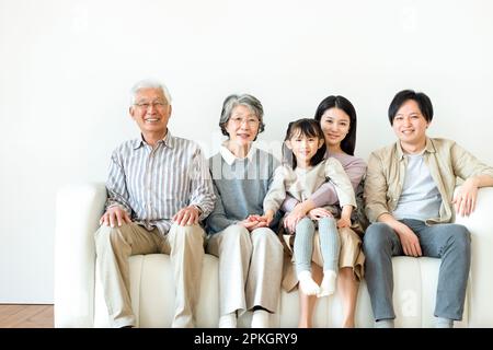 Famille de trois générations assis et souriant sur le canapé Banque D'Images