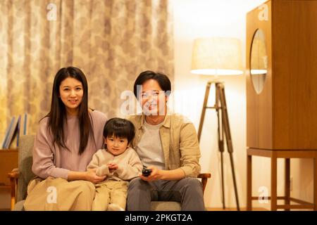 Les parents et les enfants sont assis sur le canapé et regardent la télévision Banque D'Images