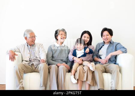 Famille de 3 générations assis et souriant sur le canapé Banque D'Images