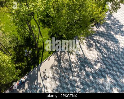 Regardez vers le bas vue aérienne sur la rue piétonne carrelée, la place avec des arbres de printemps verts ombre dans le parc de loisirs. Modèles de ville Banque D'Images