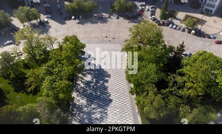 Regardez vers le bas vue aérienne sur la rue piétonne carrelée, la place avec des arbres verts ombre dans le parc de loisirs. Modèles de ville Banque D'Images