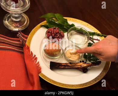 Santa Barbara, Santa Barbara, États-Unis. 5th avril 2023. Dîner de la Pâque dans une maison de Santa Barbara, CA. La Pâque est une fête printanière de 8 jours où les Juifs et beaucoup d'autres dans le monde célèbrent l'événement historique et mythique ''” et l'idée philosophique ''” des Juifs, et tous les gens ''” passant de l'esclavage (en Égypte) à la liberté en (Israël), avec l'aide grandiose de Dieu. L'assiette Seder contient six aliments différents: Le matzo, qui est du pain sans levain, symbolisant le fait que pendant l'Exode, il n'y avait pas de temps pour cuire du pain; un légume vert, symbolisant le printemps, un os de jarret d'agneau, à re Banque D'Images