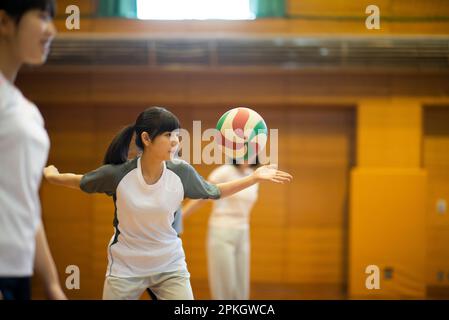 Étudiants pratiquant le volley-ball dans la salle de sport Banque D'Images