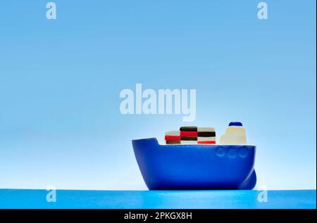 Bateau de cargaison bleu jouet naviguant sur des mers calmes avec un ciel bleu clair et un espace de copie et une faible profondeur de champ. Concept logistique fret maritime. Banque D'Images